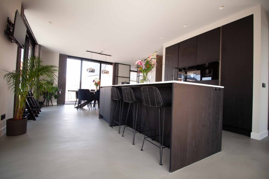 Gietvloer in donkere keuken met kookeiland